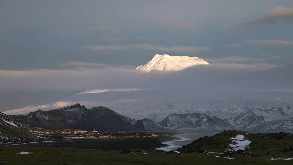 Natur bilde fra Jan Mayen, bildet er tatt fra området rundt Olinkinbyen, hvor Forsvarets stasjon ligger. Vulkanen Beerenberg stikker opp mellom skylagene og blir truffet av lav høst sol