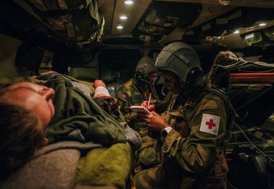 Medic i Hans Majestet Kongens Gardes sanitetstropp behandler en såret soldat i en SISU