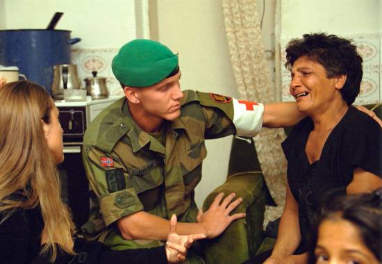 en sanitetssoldat trøster en kvinne under en husransakelse i hennes hjema medical orderly comforts a woman in her home