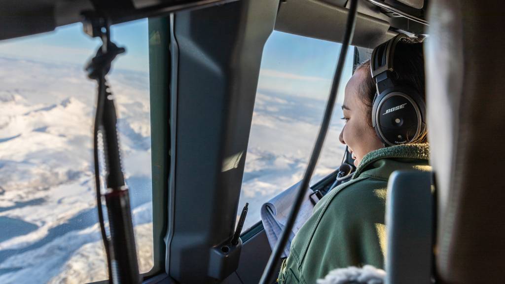 En amerikansk flyger ser på utsikt over norsk hav og vinterlandskap fra en amerikansk P-8 Poseidon.
