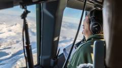 En amerikansk flyger ser på utsikt over norsk hav og vinterlandskap fra en amerikansk P-8 Poseidon.