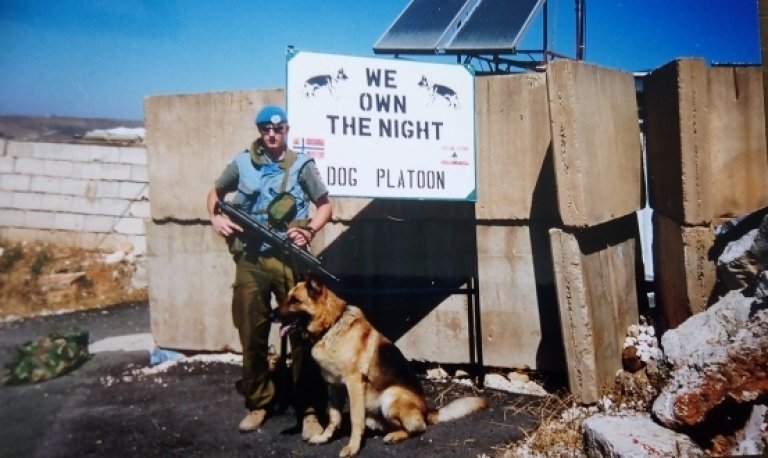 Jon Vidar Rønningen og Troy i Libanon foran et skilt med teksten We own the night og Dog Platoon.