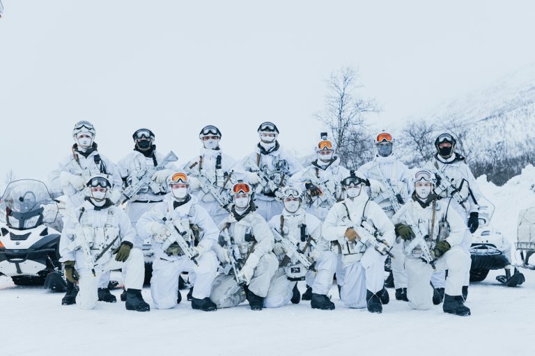 Tretten soldater  fra Nordenfjeldske etterretningsregiment oppstilt ikledd vinterkamuflasje.