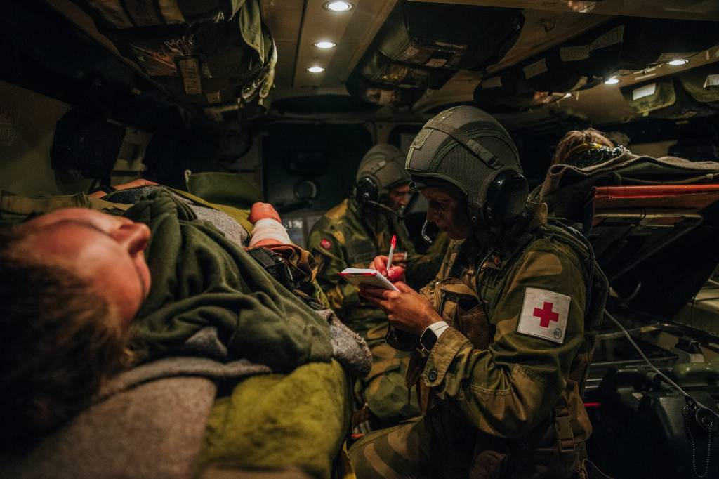 Medic i Hans Majestet Kongens Gardes sanitetstropp behandler en såret soldat i en SISU