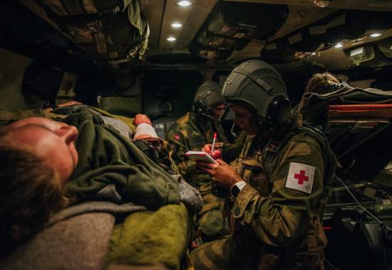 Medic i Hans Majestet Kongens Gardes sanitetstropp behandler en såret soldat i en SISU