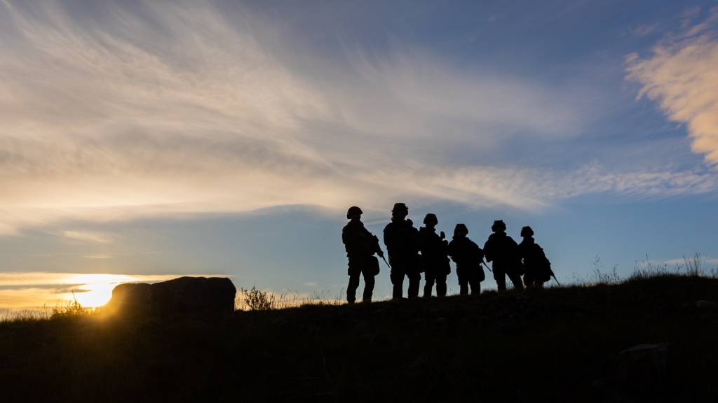 Soldater fra Heimevernets førstegangstjeneste stopper et øyeblikk og nyter midnattsolen som lyser opp Finnmarks fantastiske landskap.