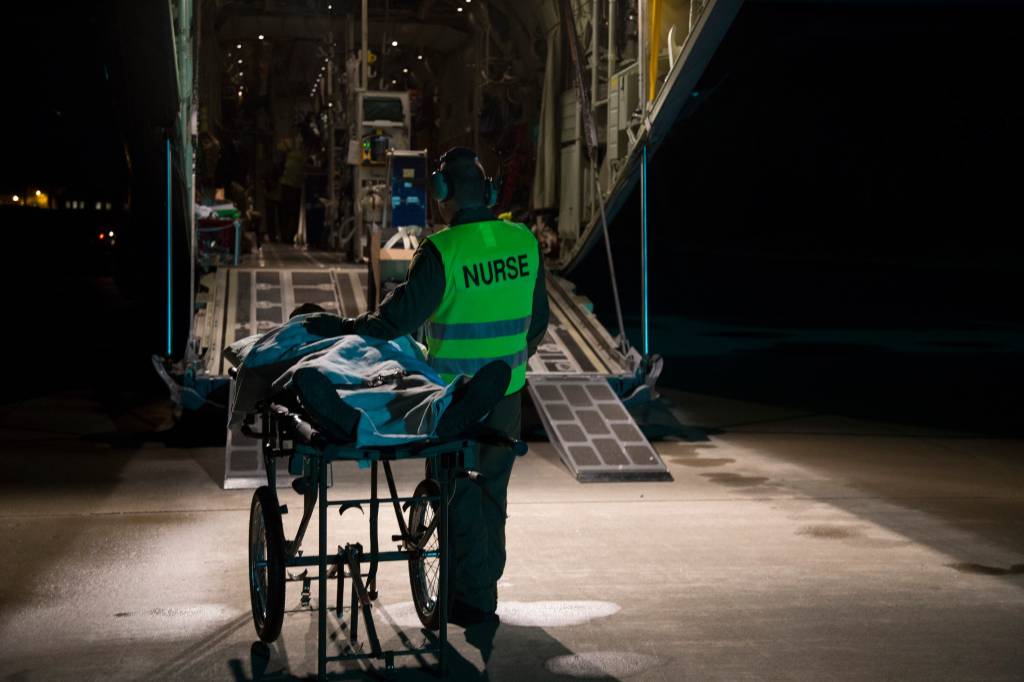 En sykepleier ivaretar en pasient som venter på å komme ombord i et Hercules transport som en del av øvelse Samaritan/A nurse safeguards a patient waiting to get aboard a Hercules transport aircraft as a part of the exercise Samaritan