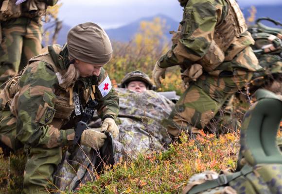 Sanitetssoldat fra Trenregimentet gjennomfører livreddende førstehjelp (MAH-drill) på en pasient. Ved å bruke en fjellduk forhindrer man at pasienten blir nedkjølt.