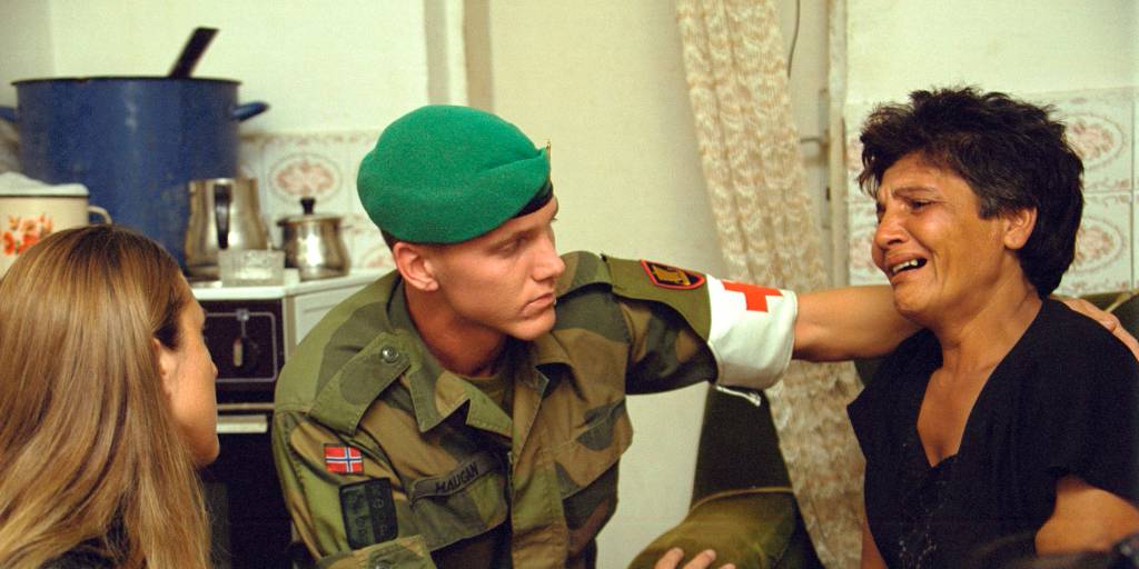 en sanitetssoldat trøster en kvinne under en husransakelse i hennes hjema medical orderly comforts a woman in her home